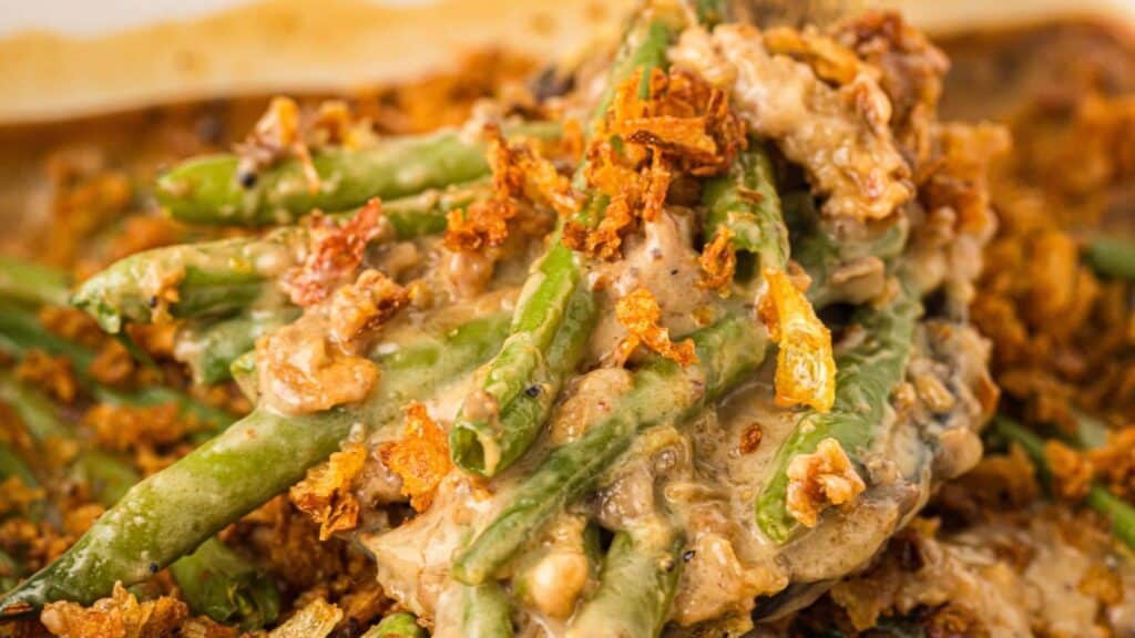 Close-up of green bean casserole topped with crispy fried onions and creamy sauce.