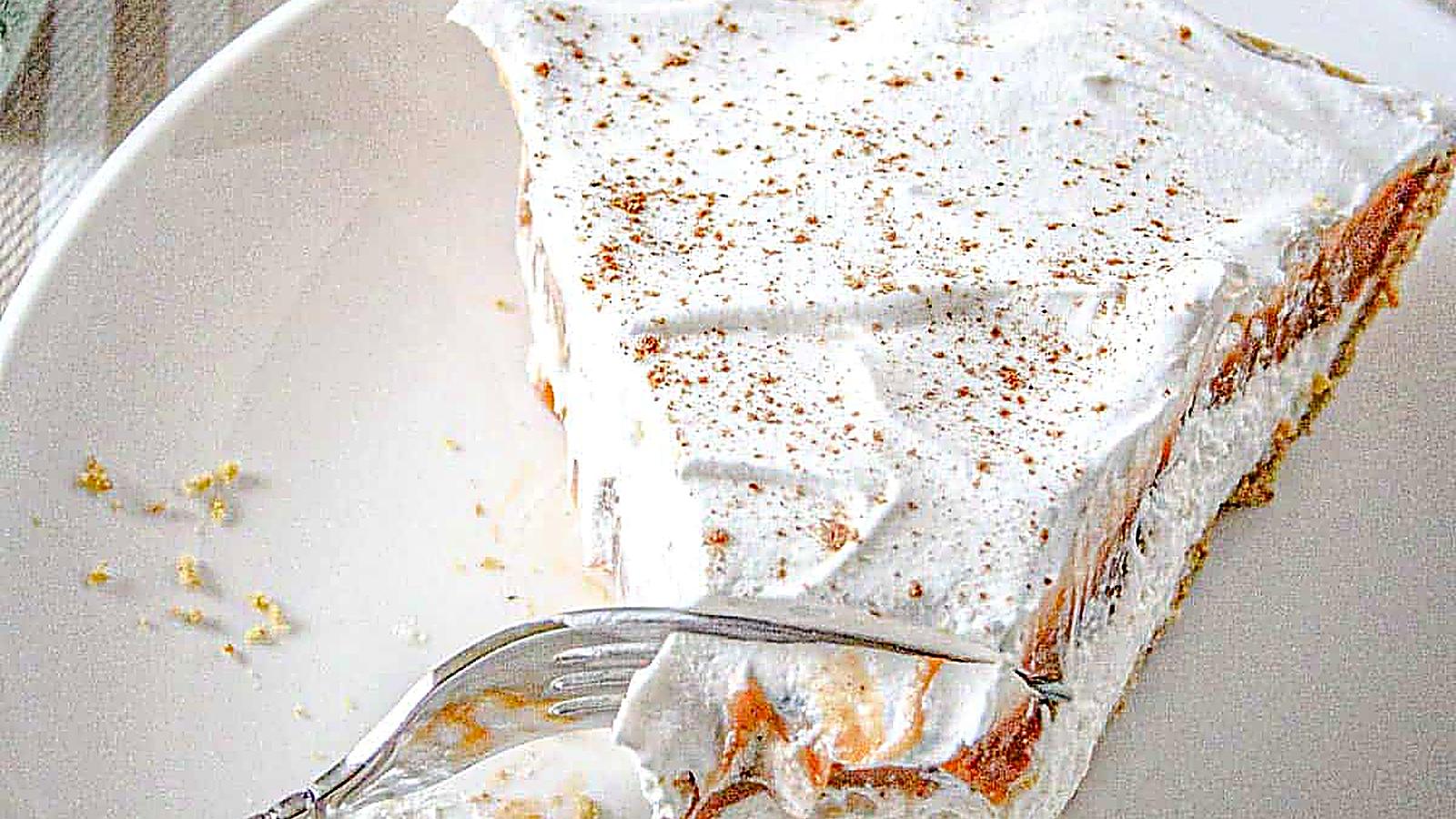 A slice of no-bake pumpkin cheesecake delight on a white plate, partially eaten with a fork resting on the plate.