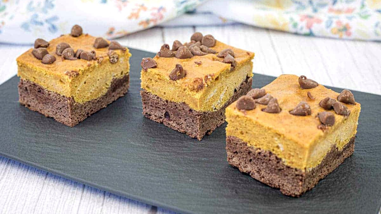 Three pieces of pumpkin brownies on a slate plate.