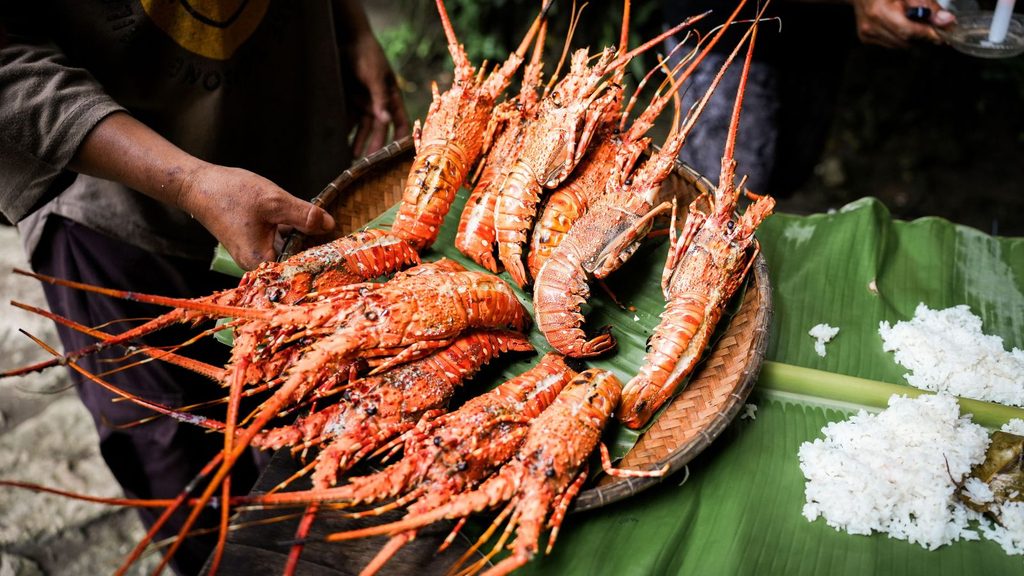 A woven basket filled with cooked, whole spiny lobsters on a banana leaf next to mounds of white rice, served at the Saba Rum and Lobster Fest.
