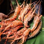 A woven basket filled with cooked, whole spiny lobsters on a banana leaf next to mounds of white rice, served at the Saba Rum and Lobster Fest.