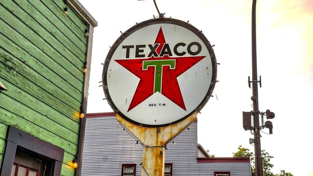 A vintage circular Texaco logo sign featuring a red star and green letter T, reminiscent of classic gas station promotions.