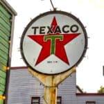 A vintage circular Texaco logo sign featuring a red star and green letter T, reminiscent of classic gas station promotions.