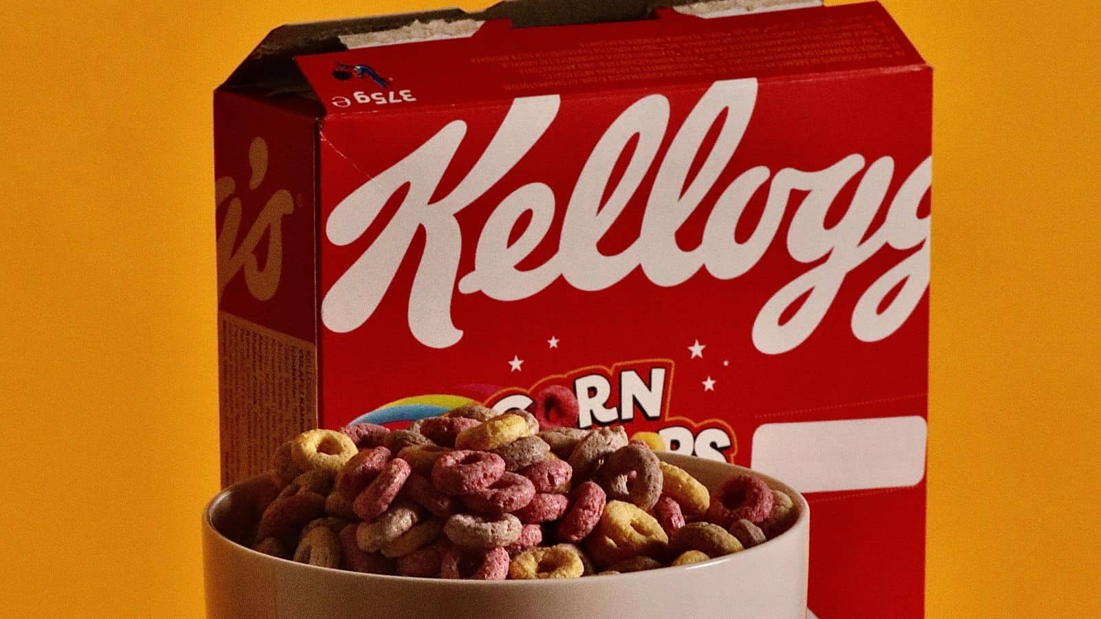 A bowl of colorful, ring-shaped cereal in front of a red Kellogg’s box, reminiscent of the cereal prizes kids loved.