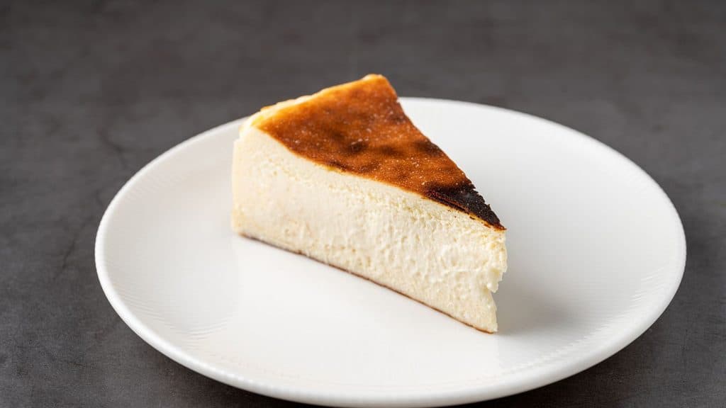 A slice of Basque burnt cheesecake served on a white plate.