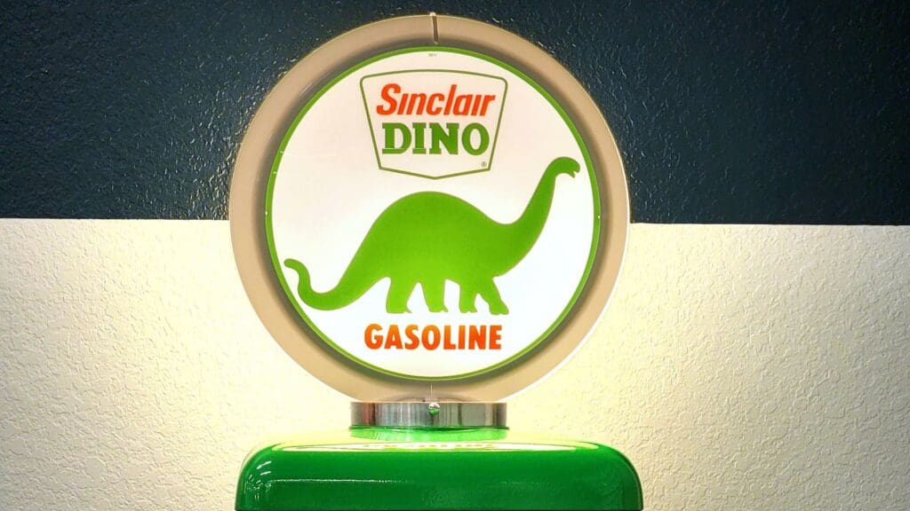 Circular Sinclair Dino gasoline sign, a classic piece of gas station promotions, featuring a green dinosaur silhouette.