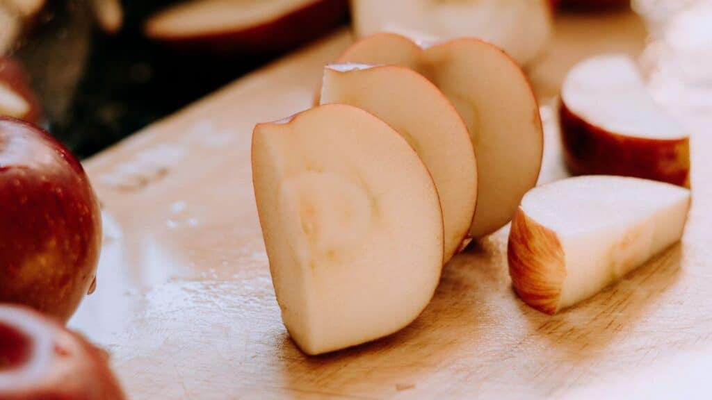 Slices of a red apple variety, suitable for baking or eating fresh, arranged on a wooden cutting board.