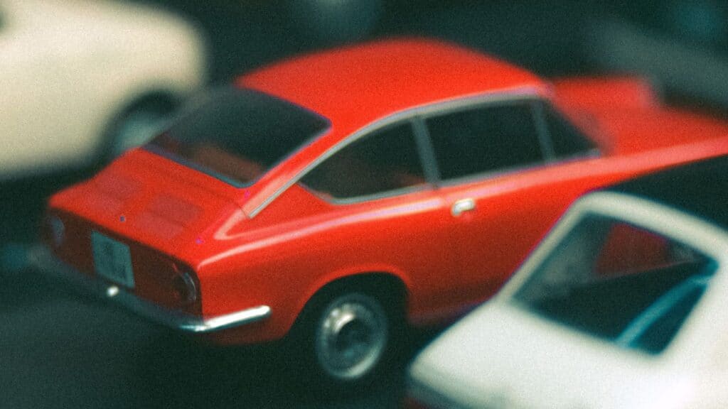 A red toy car, one of the cereal box prizes kids loved, parked between two other toy cars.