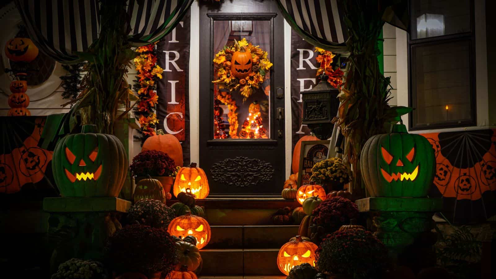 A front porch decorated for Halloween with glowing jack-o’-lanterns, autumn foliage, and “Trick or Treat” banners that comply with HOA Halloween rules.