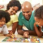 A family of four sitting on the floor playing a board game together.