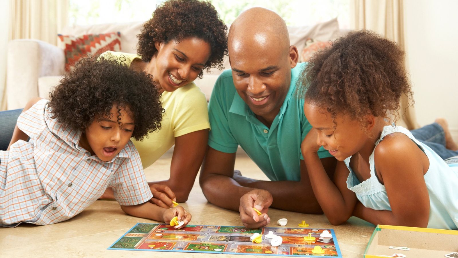 A family of four sitting on the floor playing a board game together.