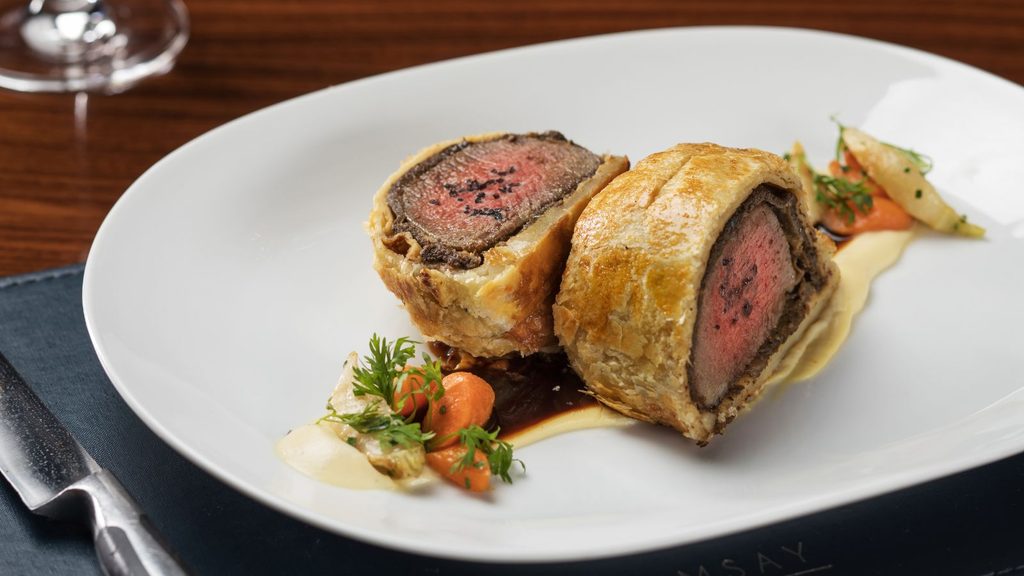 Two slices of beef Wellington, similar to those made in Las Vegas classes, served on a plate with pur&eacute;e and roasted carrots.