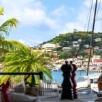 View from a Grenada restaurant patio overlooking a harbor and a hillside city with colorful buildings.