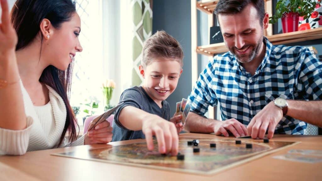 A mother, father, and son smiling while playing fall board games and puzzles together at a table.