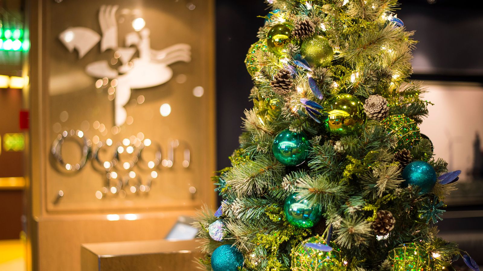 A decorated Christmas tree with green and gold ornaments beside a sign that reads Ocean.