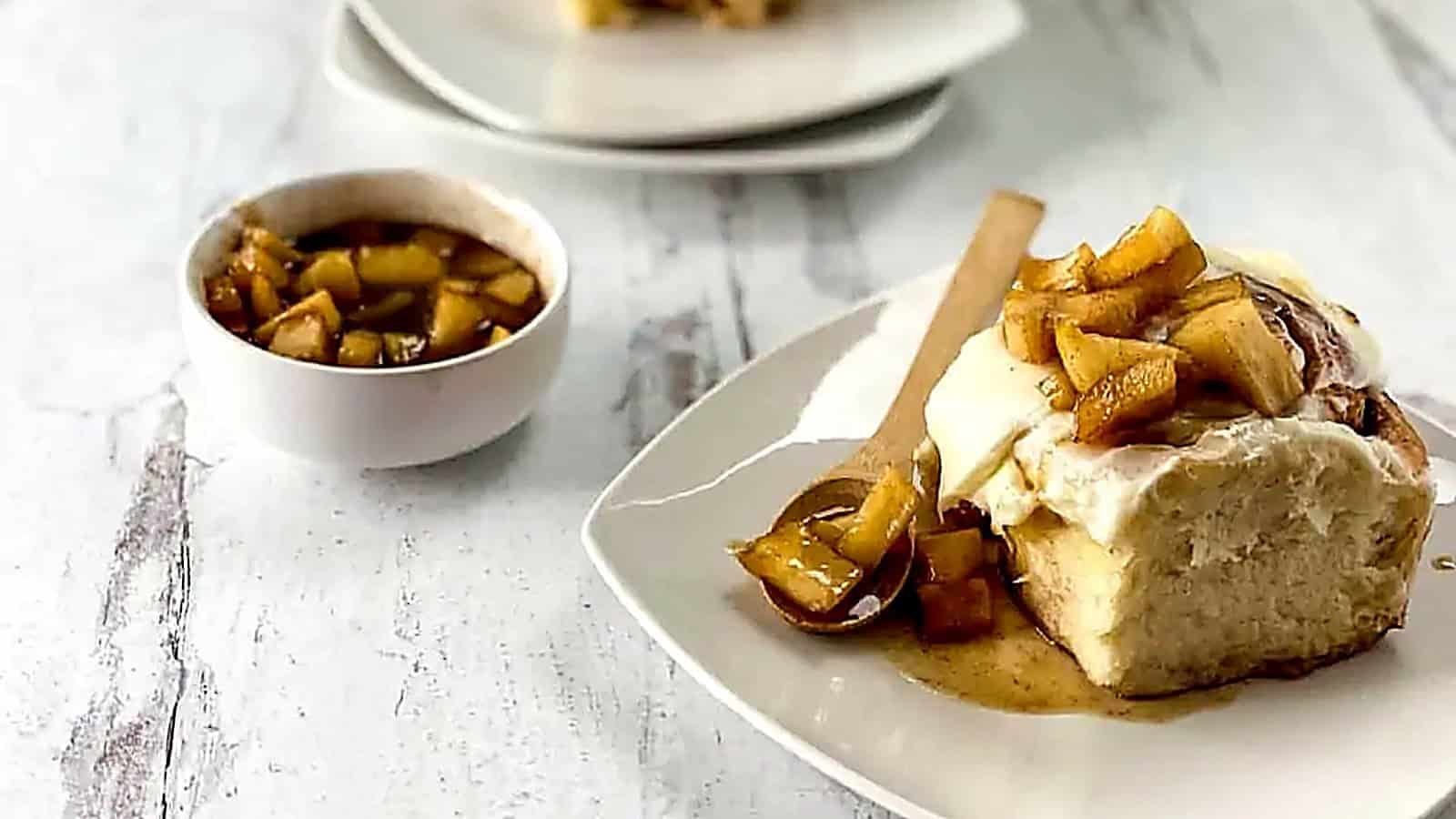 An apple cinnamon roll on a plate with a spoon.