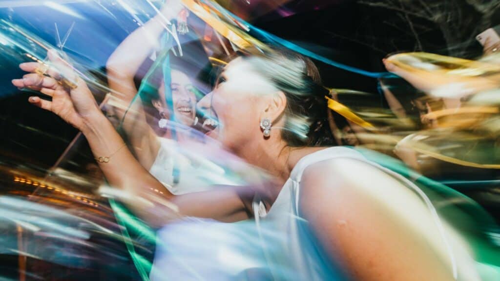 Two women in white dresses laughing and dancing with colorful ribbons in a motion-filled, one hour photo style memory.