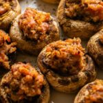 A platter of cooked mushroom caps stuffed with a savory breadcrumb mixture.