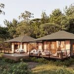Two luxury safari tents with wooden decks and seating areas located in a forest clearing, perfect for hotel openings in 2027.