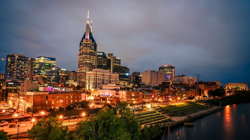 Nashville skyline at dusk reflecting off the Cumberland River by the AT&T Building, a great time to visit for fall hotel rates.