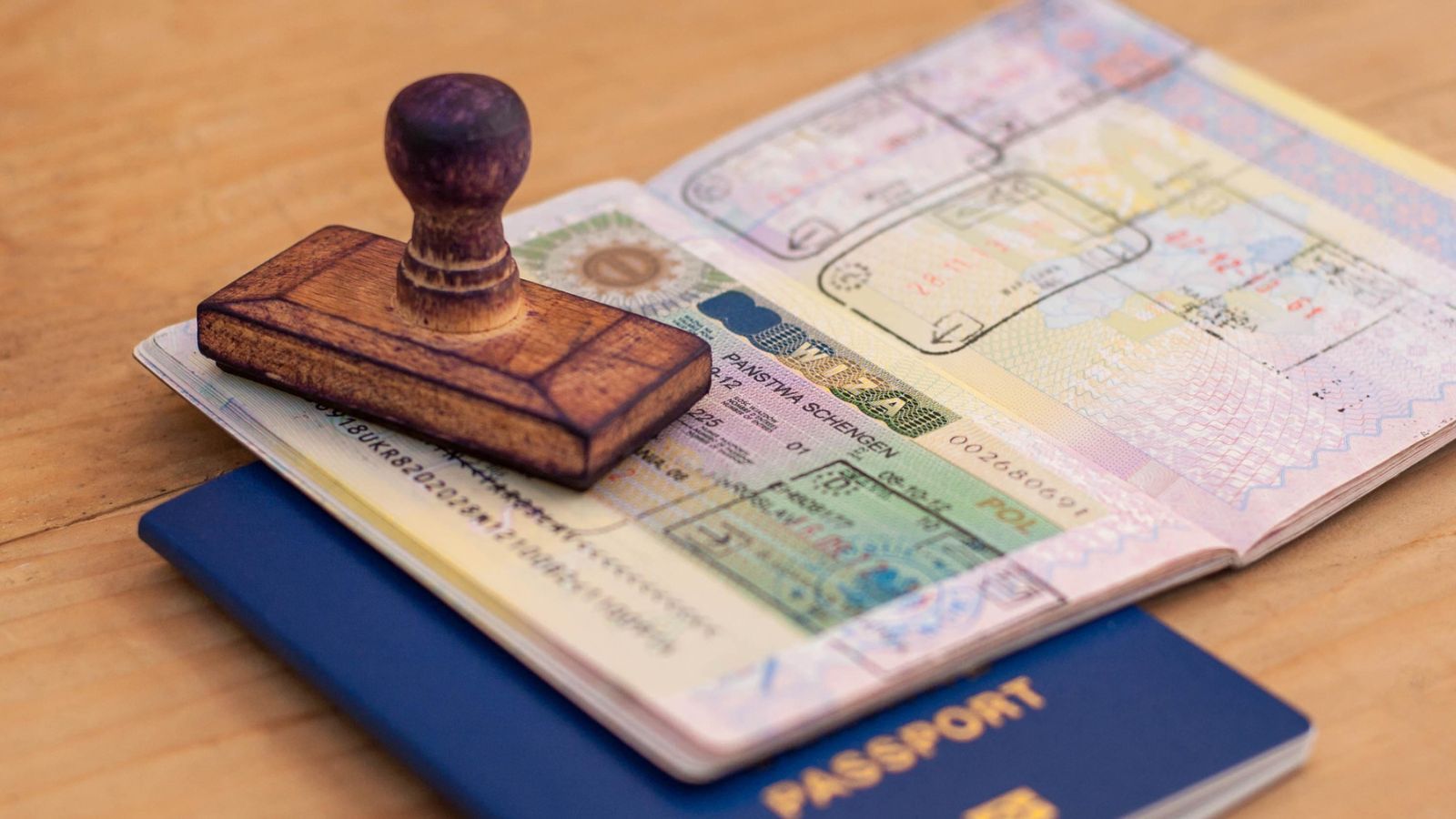 A wooden stamp resting on an open passport with a Schengen visa.