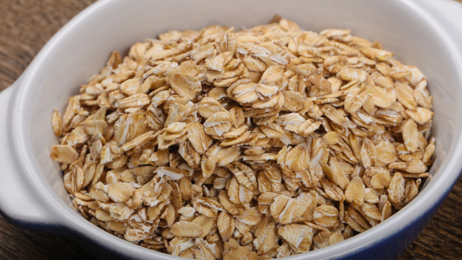 A white bowl filled with rolled oatmeal.
