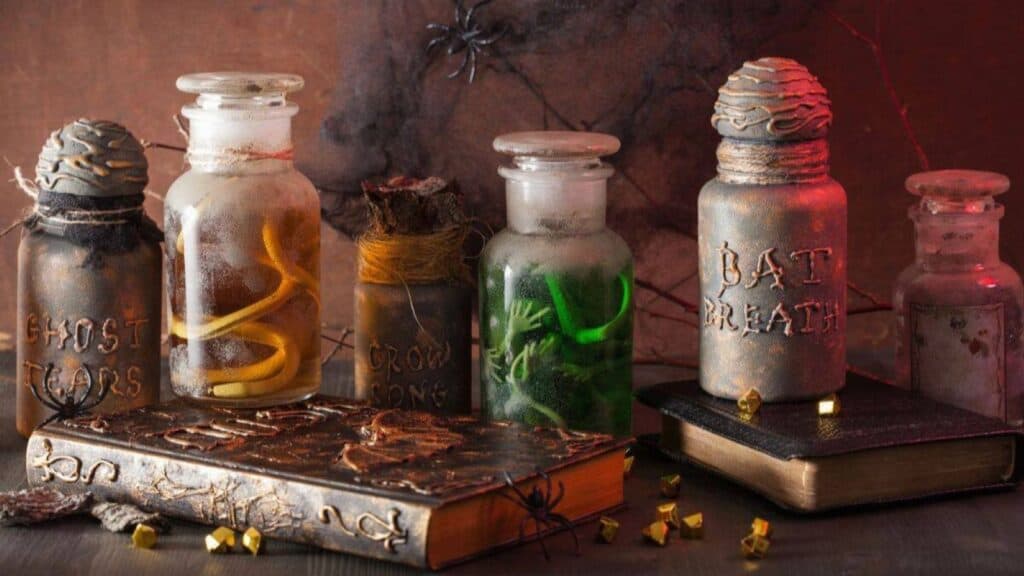 Recycled Halloween decorations featuring glass apothecary jars labeled “Ghost Tears,” “Crow Song,” and “Bat Breath” arranged with two old books on a table.