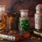 Recycled Halloween decorations featuring glass apothecary jars labeled “Ghost Tears,” “Crow Song,” and “Bat Breath” arranged with two old books on a table.