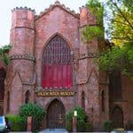 The Salem Witch Museum, a historic stone building with a large arched window, surrounded by trees.