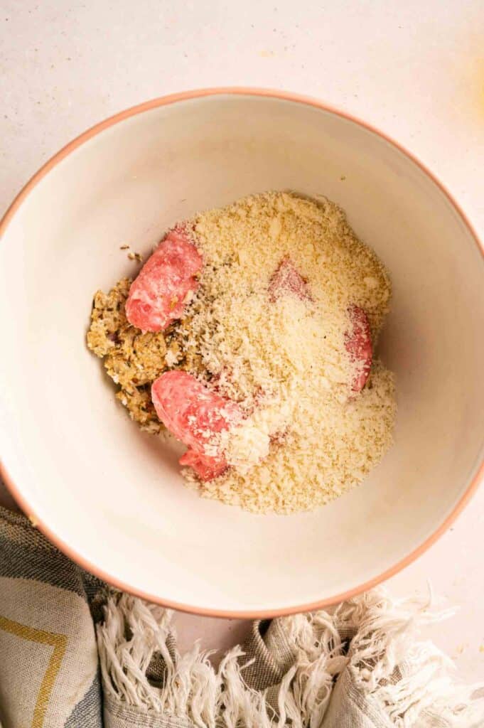 Raw ground meat, a savory mixture, and breadcrumbs in a mixing bowl.