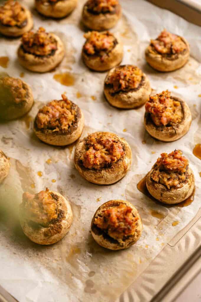 Baked stuffed mushrooms on a parchment-lined baking sheet.