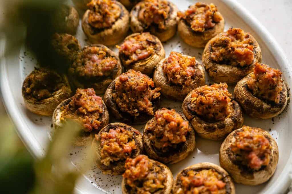 A platter of baked, stuffed mushrooms topped with breadcrumbs.