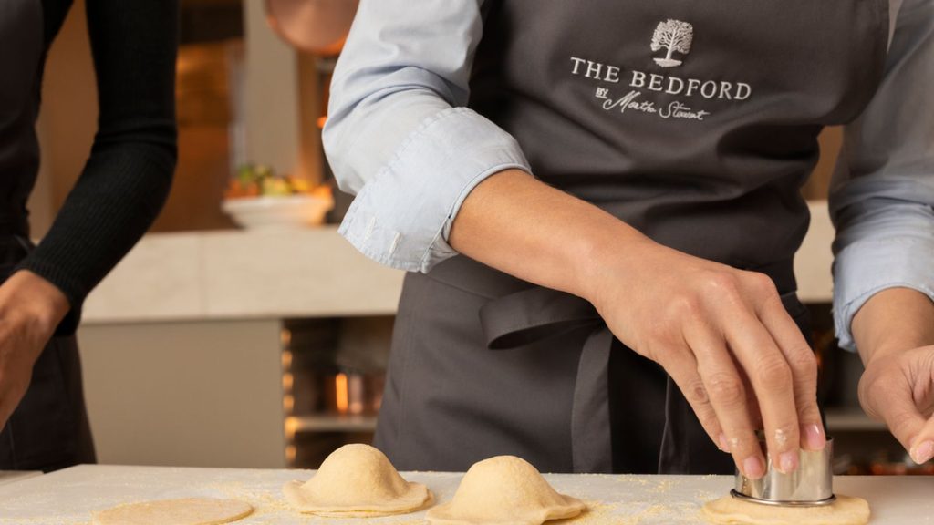 Person wearing a &ldquo;The Bedford by Martha Stewart&rdquo; apron uses a circular cutter on pasta dough.