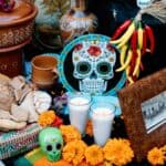 Día de los Muertos altar with marigolds, candles, sugar skulls, a ceramic bowl, and food offerings, representing countries with Halloween-like traditions.