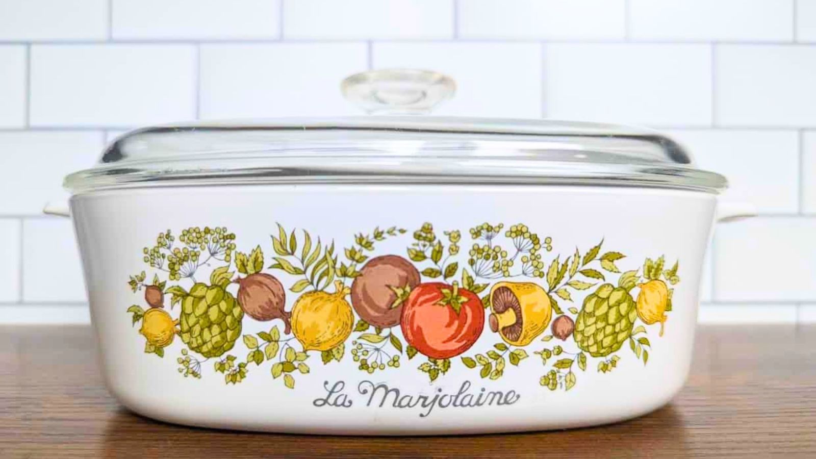 White rectangular Corningware casserole dish with a glass lid, decorated with a colorful pattern of garden vegetables and the script text “La Marjolaine.”