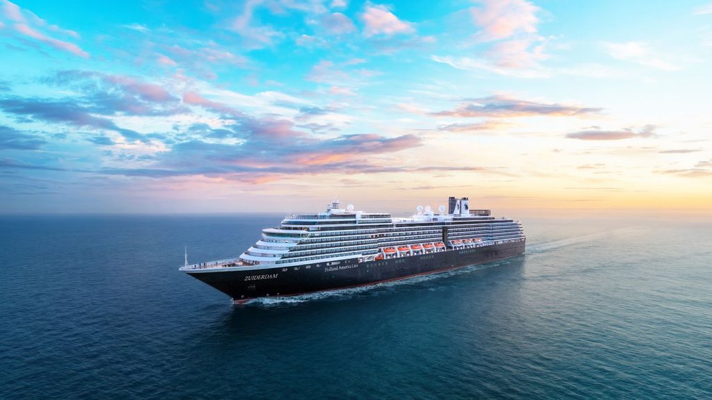 Holland America Line cruise ship Zuiderdam sailing on the ocean during a sunset.