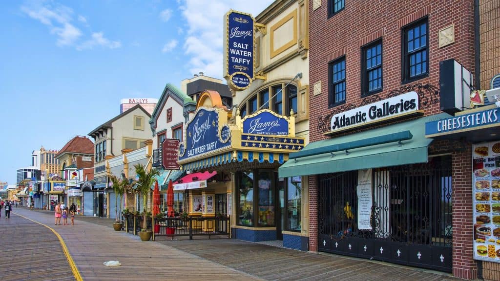 A view of the Atlantic City boardwalk featuring James Salt Water Taffy, Atlantic Galleries, and other storefronts.
