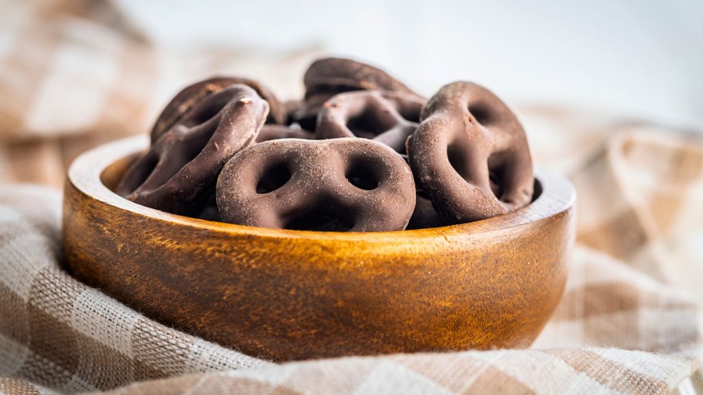 A wooden bowl filled with chocolate-covered pretzels, perfect for National Chocolate Covered Pretzel Day.