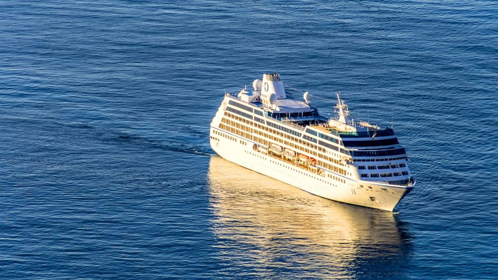 A white cruise ship sailing across dark blue water.