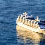 A white cruise ship sailing across dark blue water.