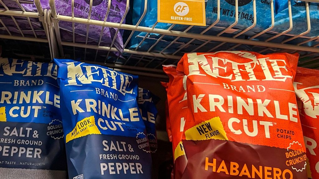 Kettle Brand Krinkle Cut potato chip bags in Salt & Fresh Ground Pepper and Habanero flavors on a store shelf, with a gluten-free sign above.