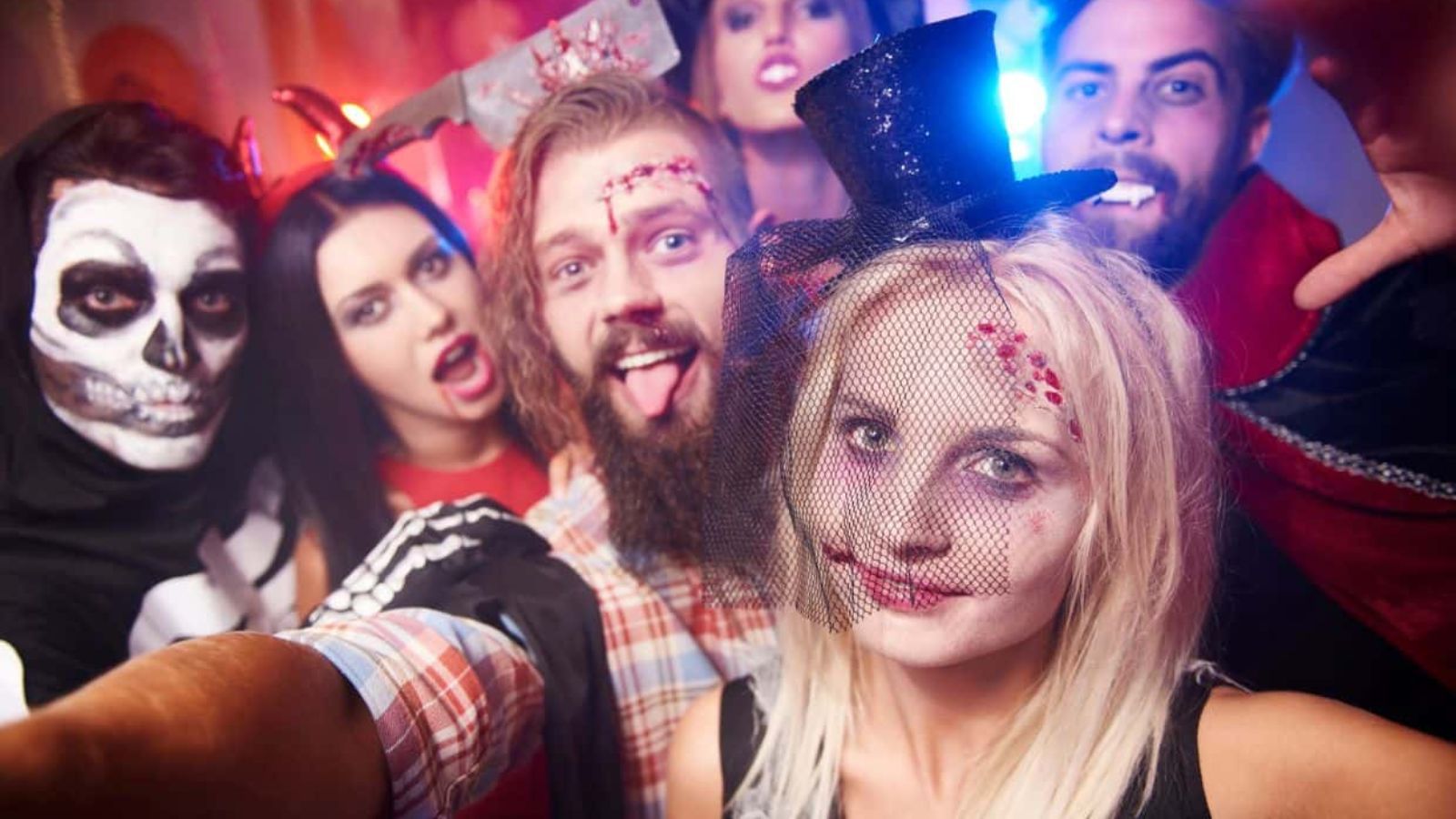 A group of friends in Halloween costumes and makeup posing for a selfie.