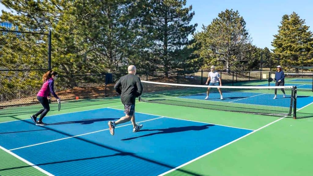 Four people playing pickleball on an outdoor court.
